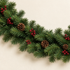 Close-up of real-touch green artificial pine garland with berry clusters and pine cones