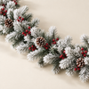 Close-up of white flocked artificial pine garland with berry clusters and pine cones