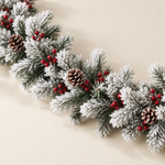 Close-up of white flocked artificial pine garland with berry clusters and pine cones